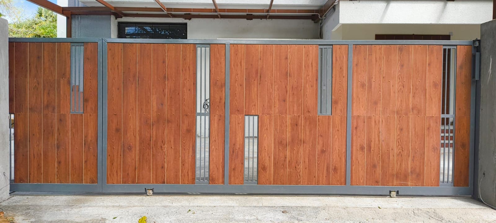 Automated sliding gate with gunmetal steel frame and wood-finish panels